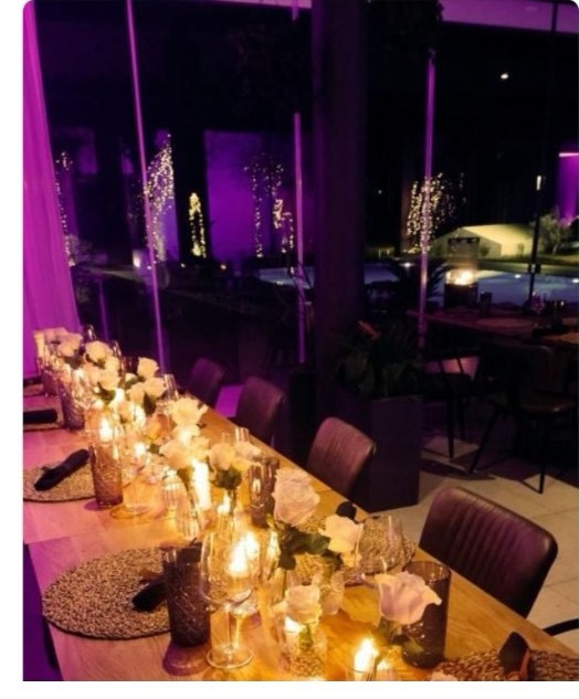 A candlelit dining table set beside the illuminated pool and vineyard, decorated for the holiday season